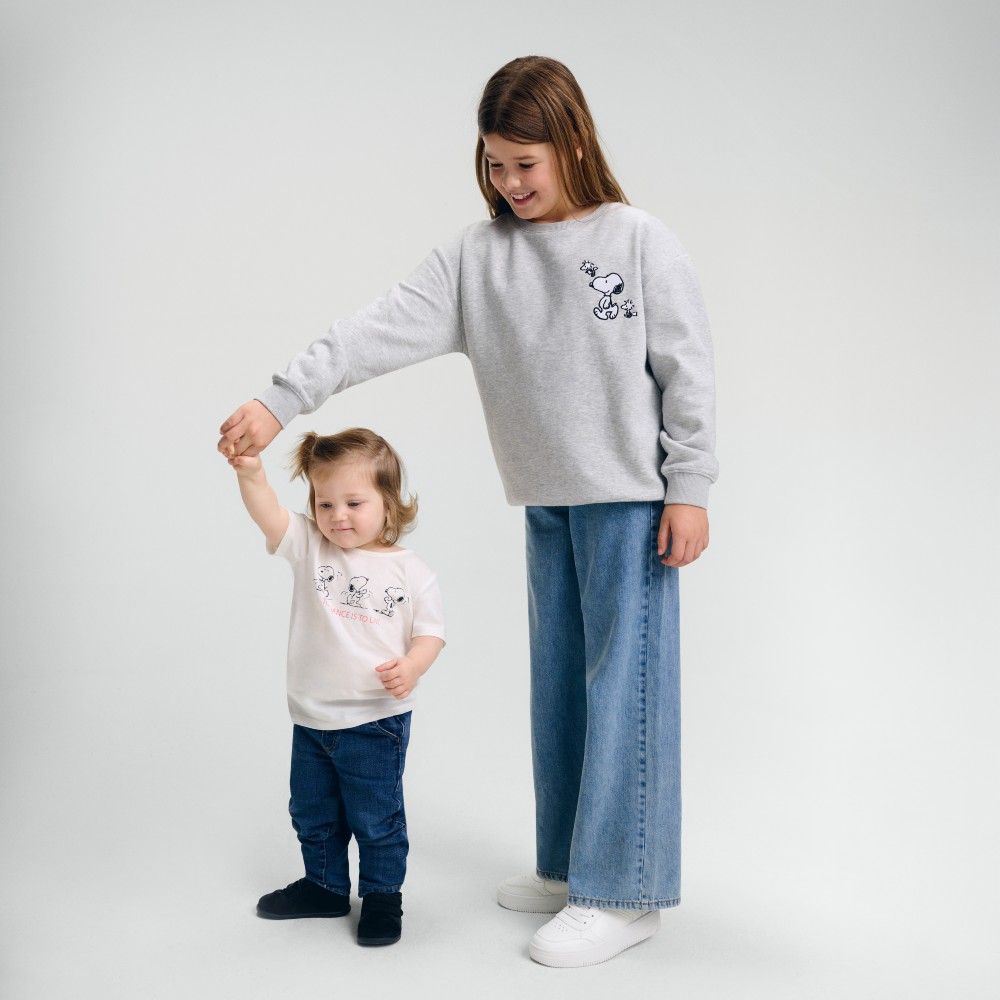 A girl holding the hand of a younger child beside her 