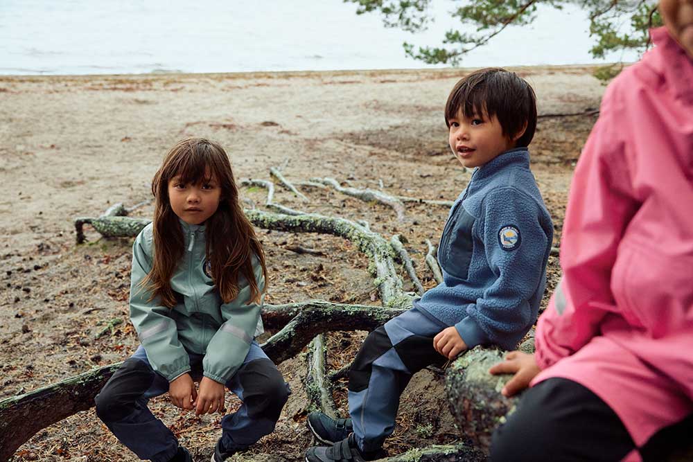 Three children sat on branches by the sea