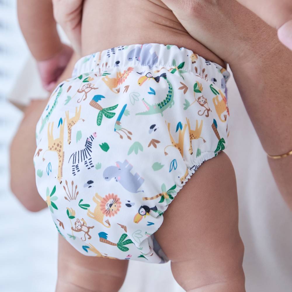 A baby being held up wearing a colourful printed nappy by Bambino Mio 