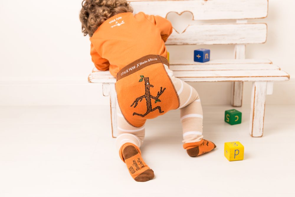 A baby's shown wearing leggings by Blade and Rose with Stick Man on the bottom and legs