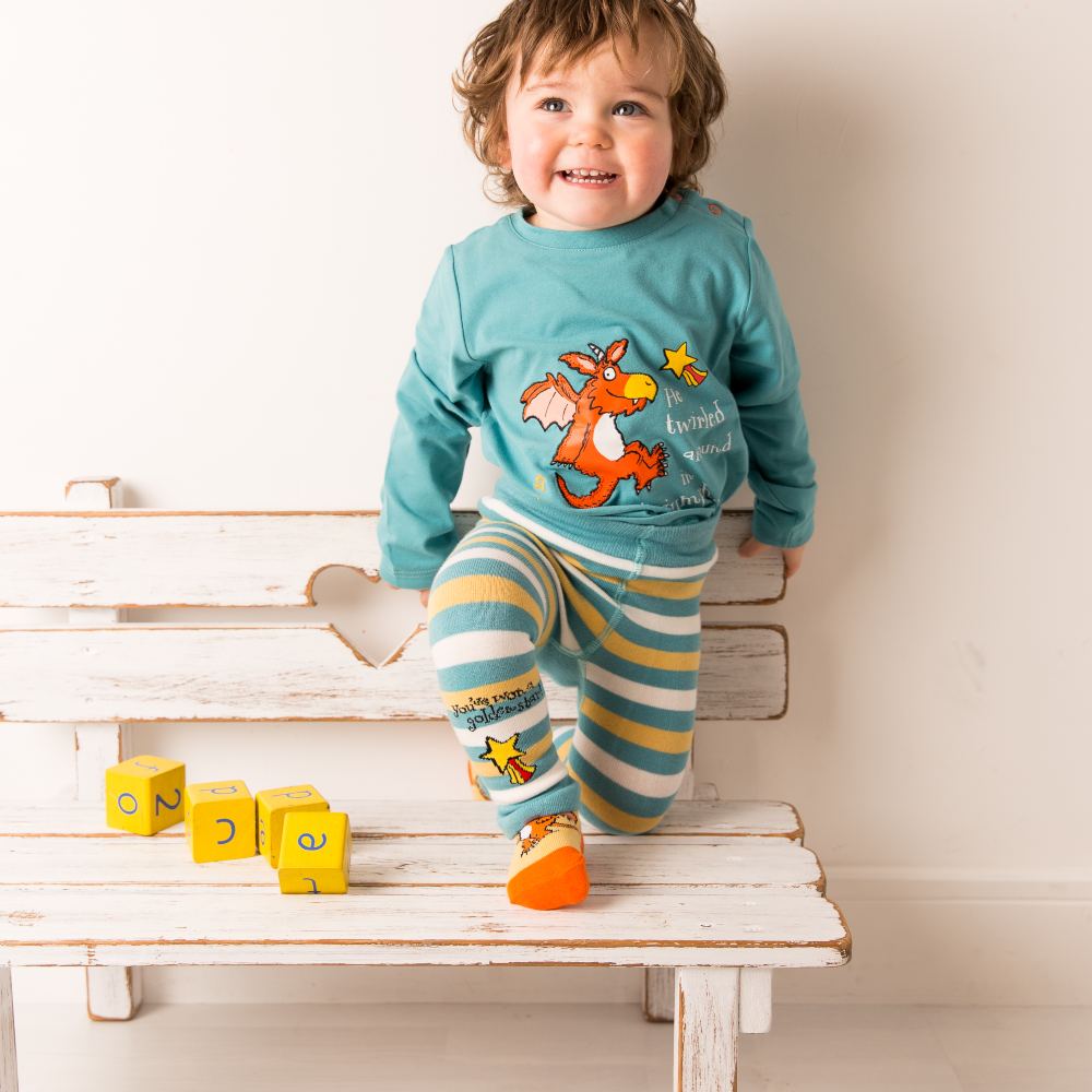 A young child knelt on a white bench wearing an outfit from Blade & Rose's Zog range 