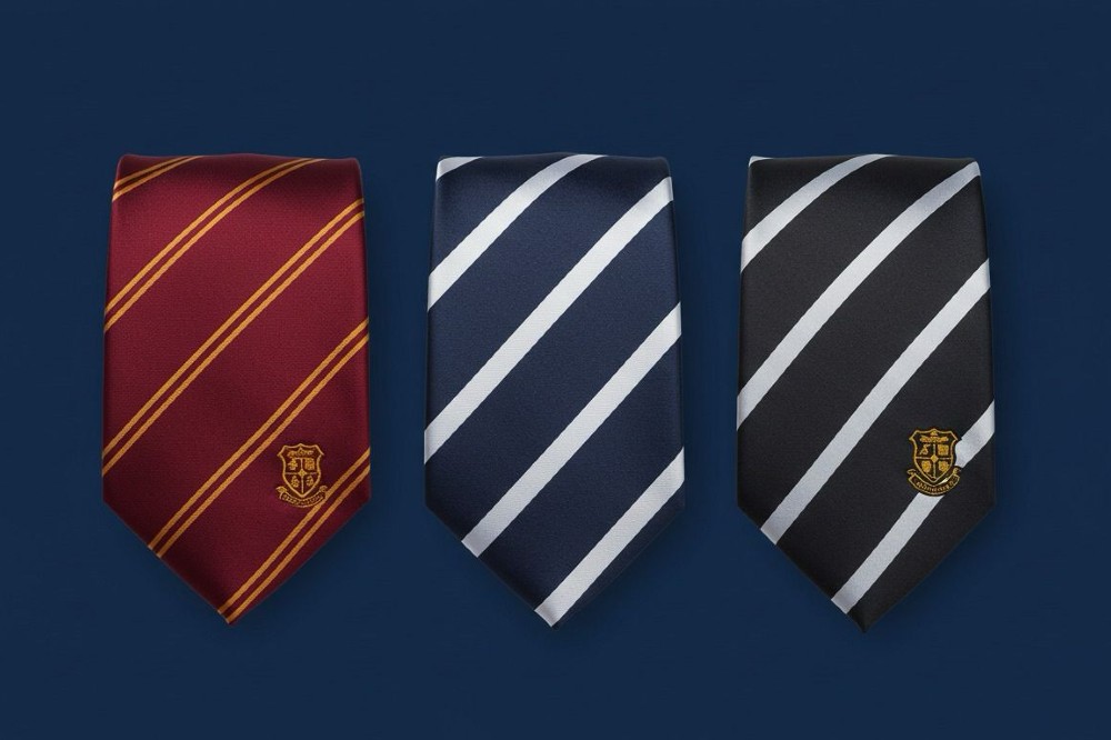 Three school ties by Charles London displayed on a blue background