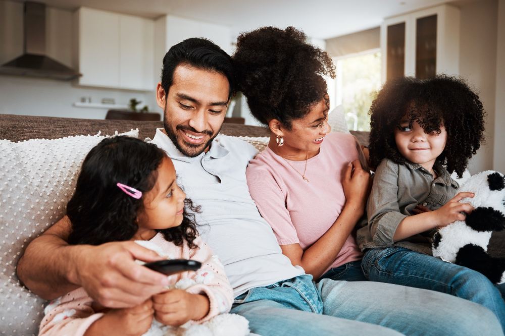 A smiling family sat on a sofa