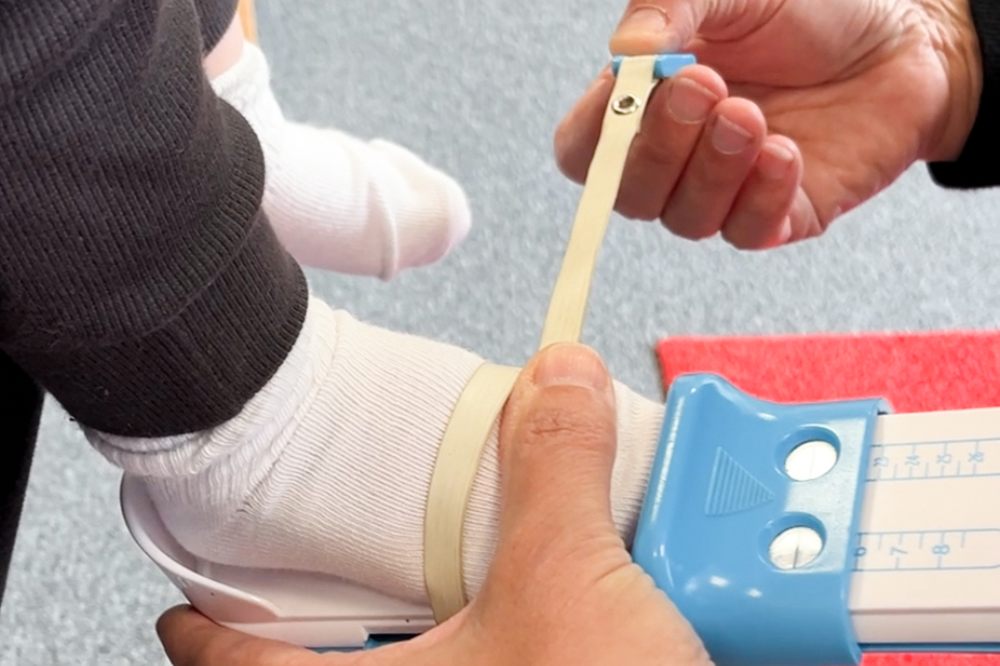 A child's foot being measured with a gauge