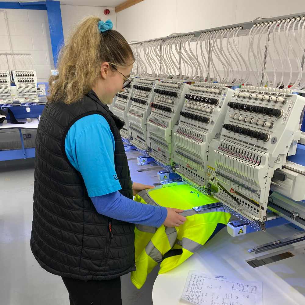 A woman working on an embroidery machine at Identity