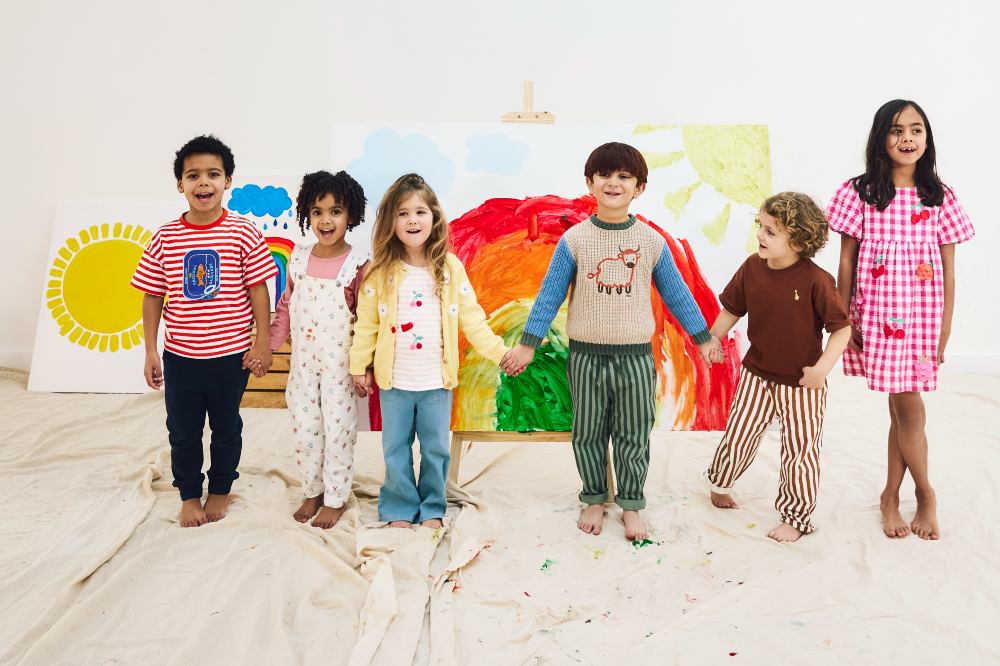 A row of children in a studio with paintings to celebrate 10 years of JoJo Maman Bebe's B Corp status