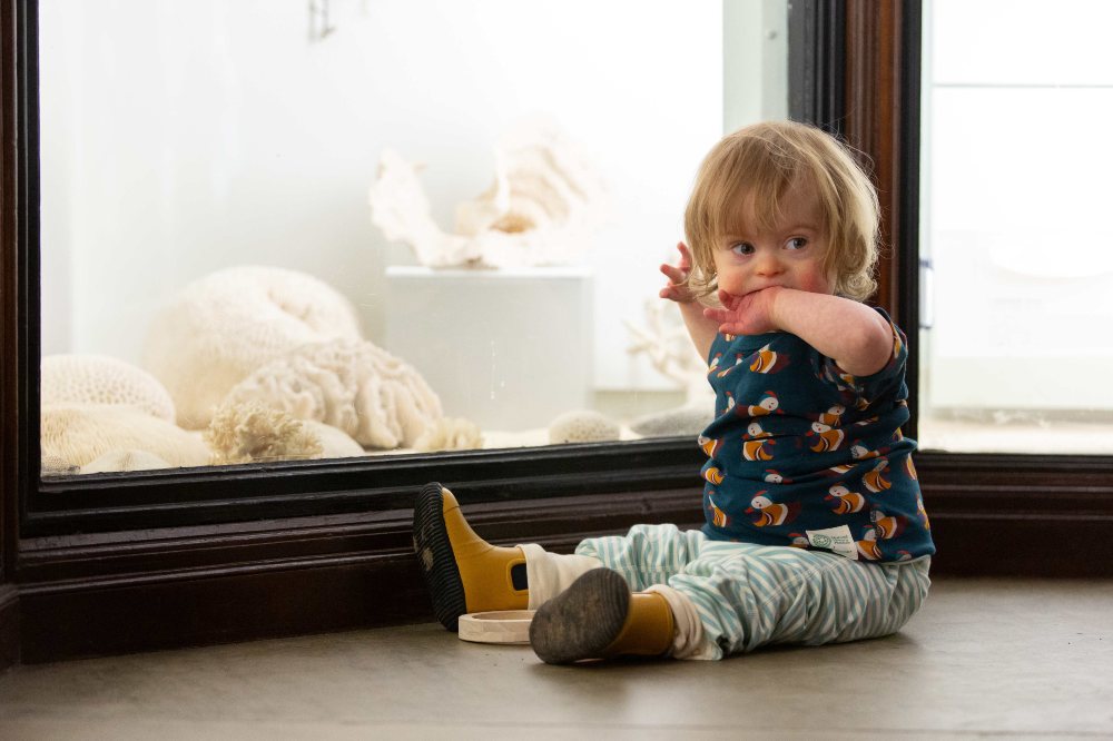A young child sat on the floor by a cabinet in the Natural History Museum