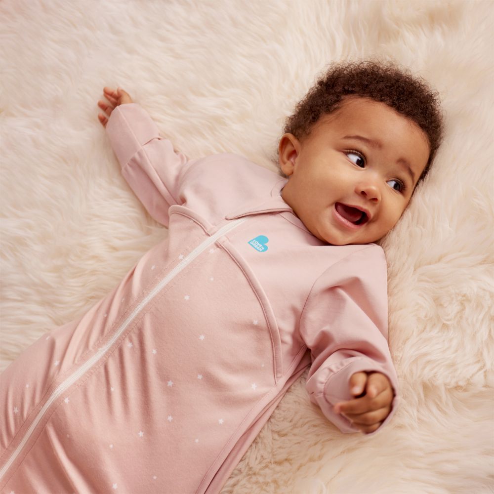 A baby in a pink sleep suit by Love to Dream