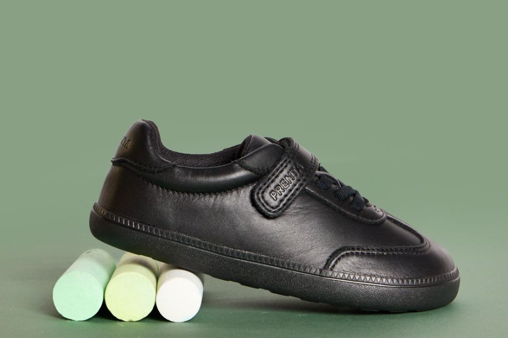 A child's black barefoot school shoes displayed on large sticks of chalk