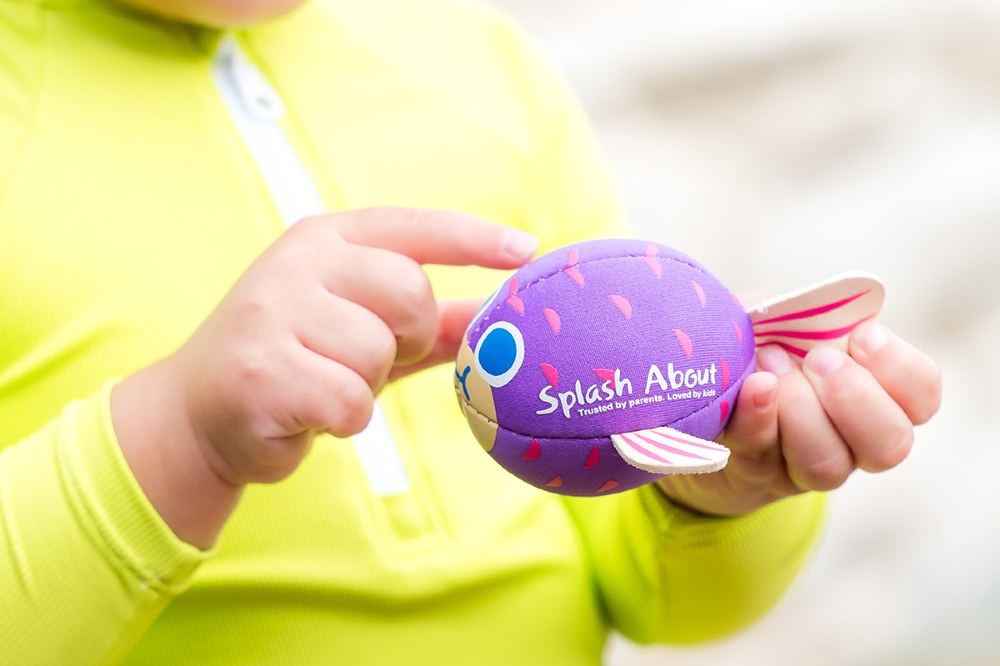 A young child holding a Splash About puffa fish bath toy
