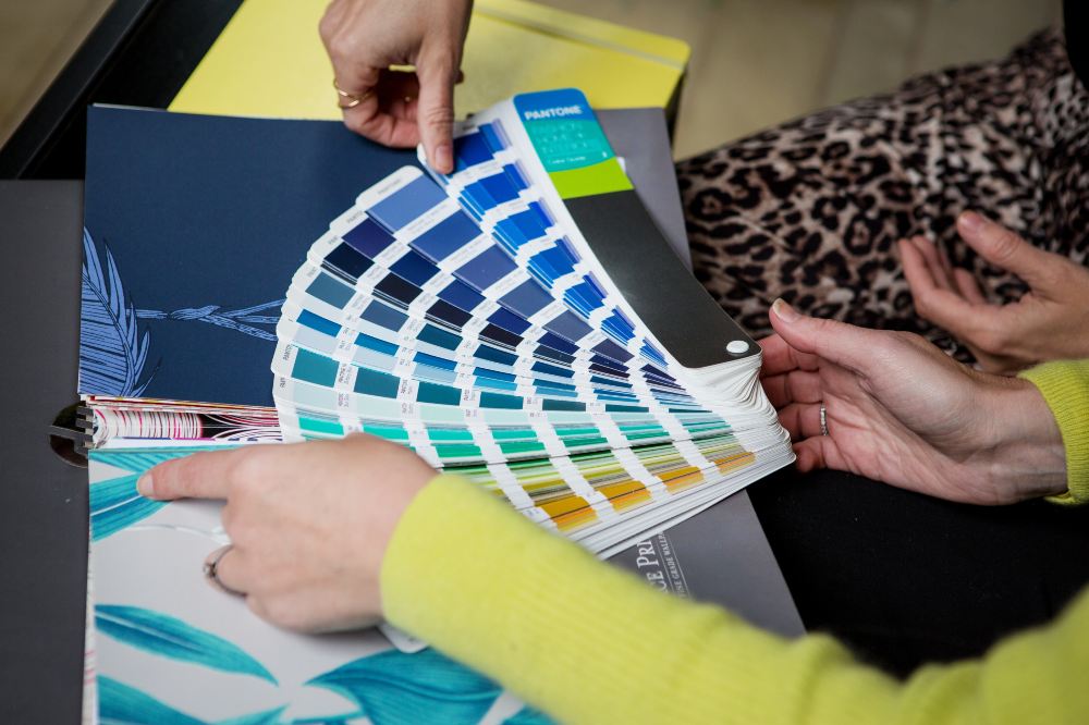 Two people's hands shown looking at colour swatches 