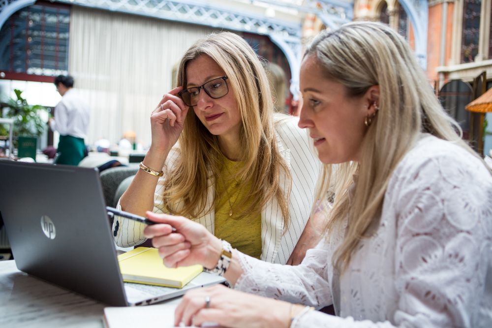 Two woman at a desk looking at a laptop 
