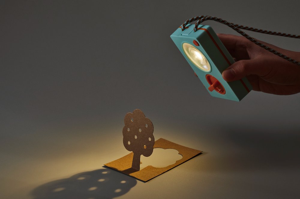 Someone holding a DIY Flashlight by Ambessa Play against a cut out of a tree to cast a shadow