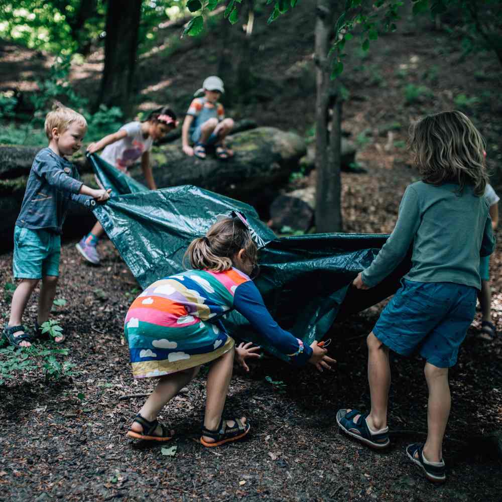 A group of children outside in a wood building a den 