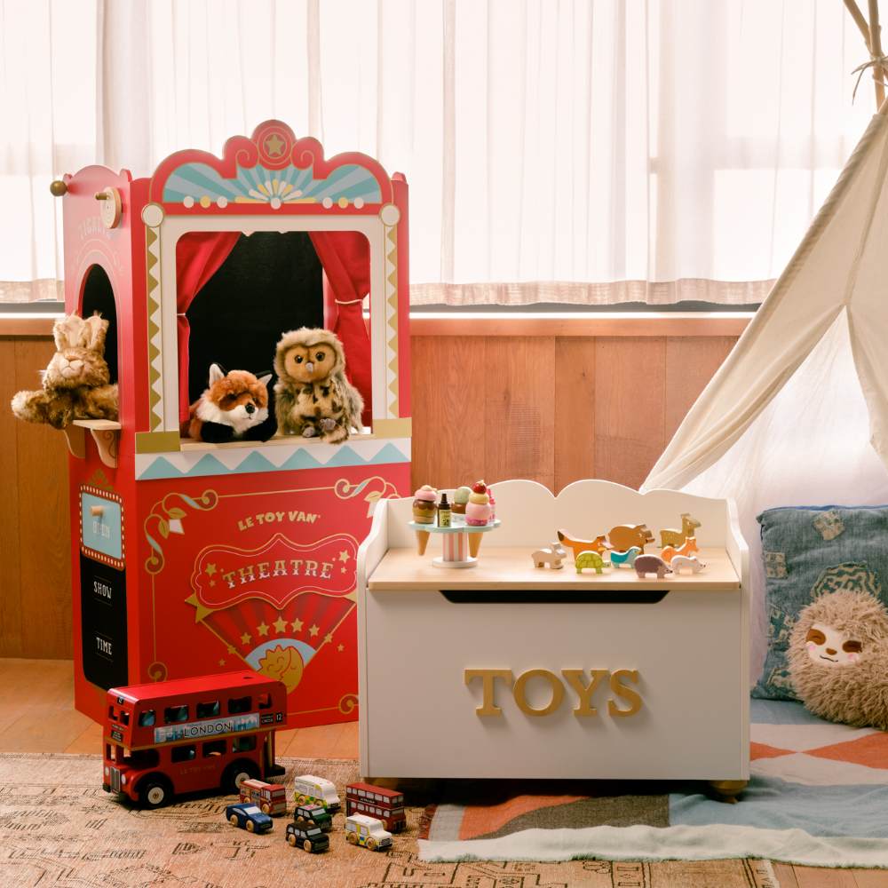 A children's puppet show, toy box and teepee displayed in a hotel room 