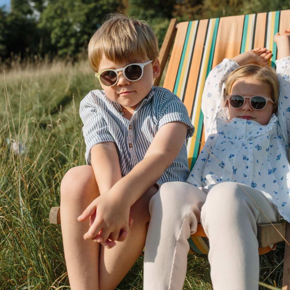 Two children sat outside in a deckchair wearing sunglasses by Leosun 