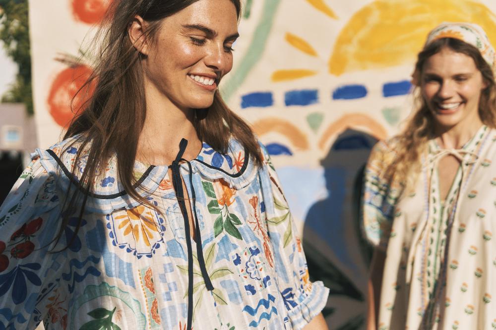 Two women stood outside wearing bright coloured floral dresses