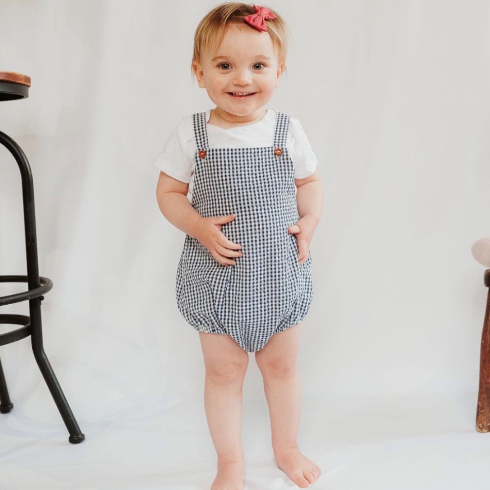 A child wearing a blue playsuit and white T-shirt 