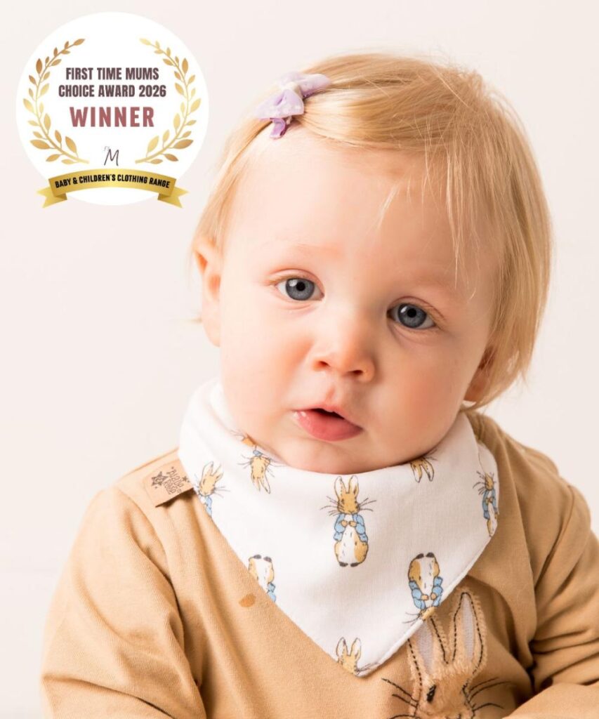 A baby wearing a bandana bib and top from Blade & Rose's Peter Rabbit Neutral Collection