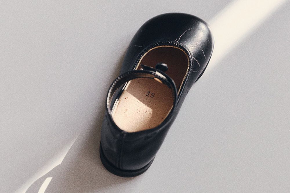 A child's single black shoe by Bundgaard on a white background