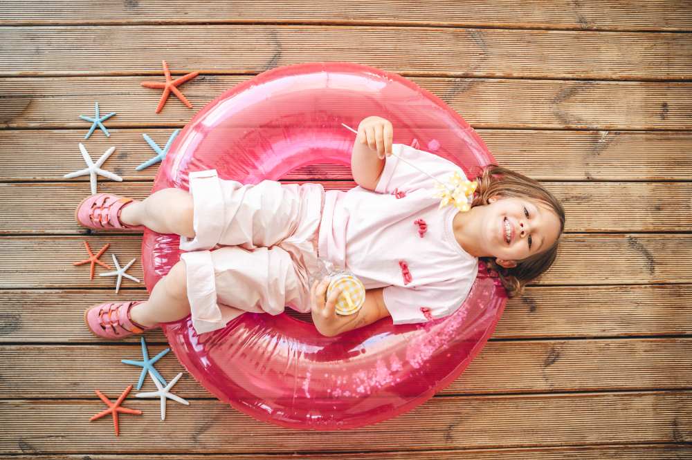 A girl lying in a red rubber ring with star fish on the floor