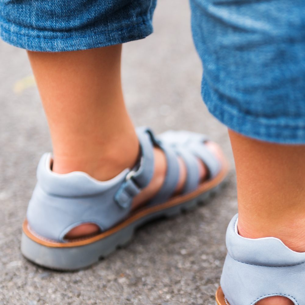 A child's feet shown wearing pale blue summer sandals 