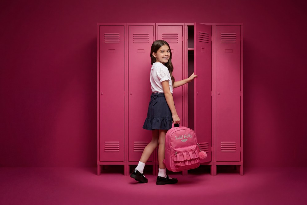 A girl in Lelli Kelly Schoolwear holding a pink ruck sack while opening a pink school locker