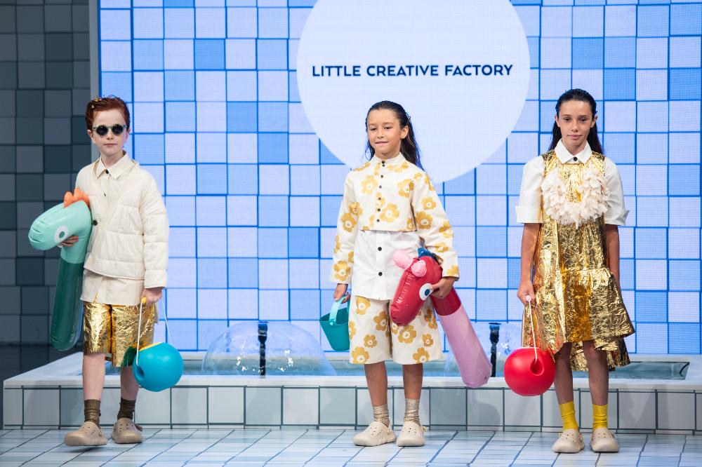Three children stood on a stage at the Splash! Fashion Show at Pitti Bimbo 103