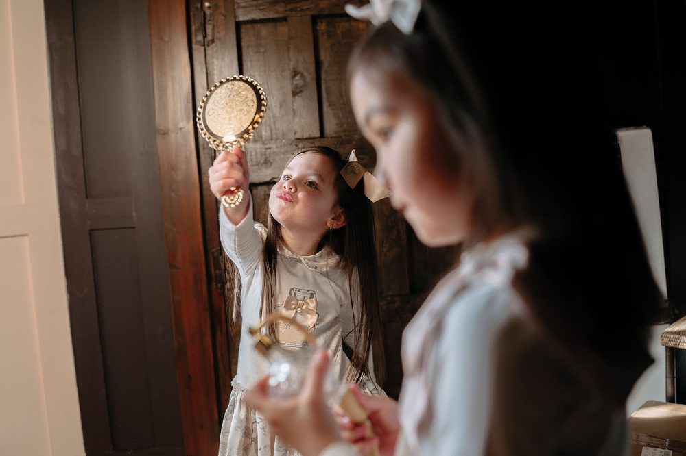 Two girls on a photoshoot with one looking into a hand mirror