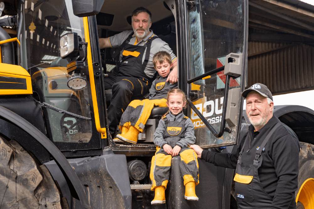 Two children in a JCB vehicle wearing outwear from the JCB x Spotty Otter collaboration