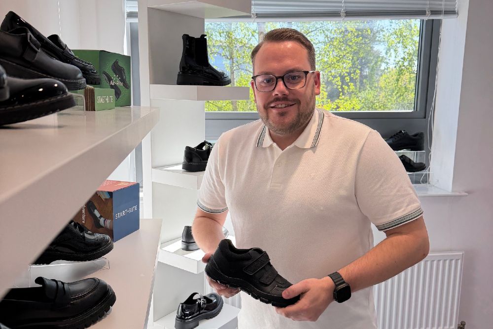 Callum Linger Brand Trainer at Start-Rite Shoes holding up a child's black school shoe