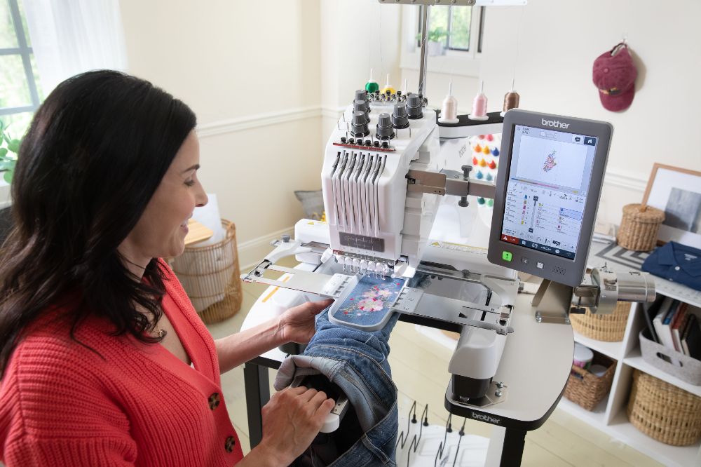 A woman stitching an embroidery onto denim jeans using a Brother embroidery machine