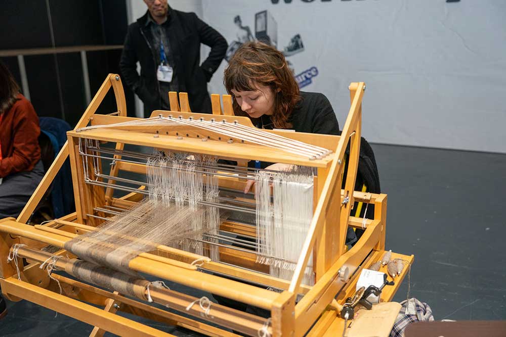 A woman sat operating a sewing–spinning machine