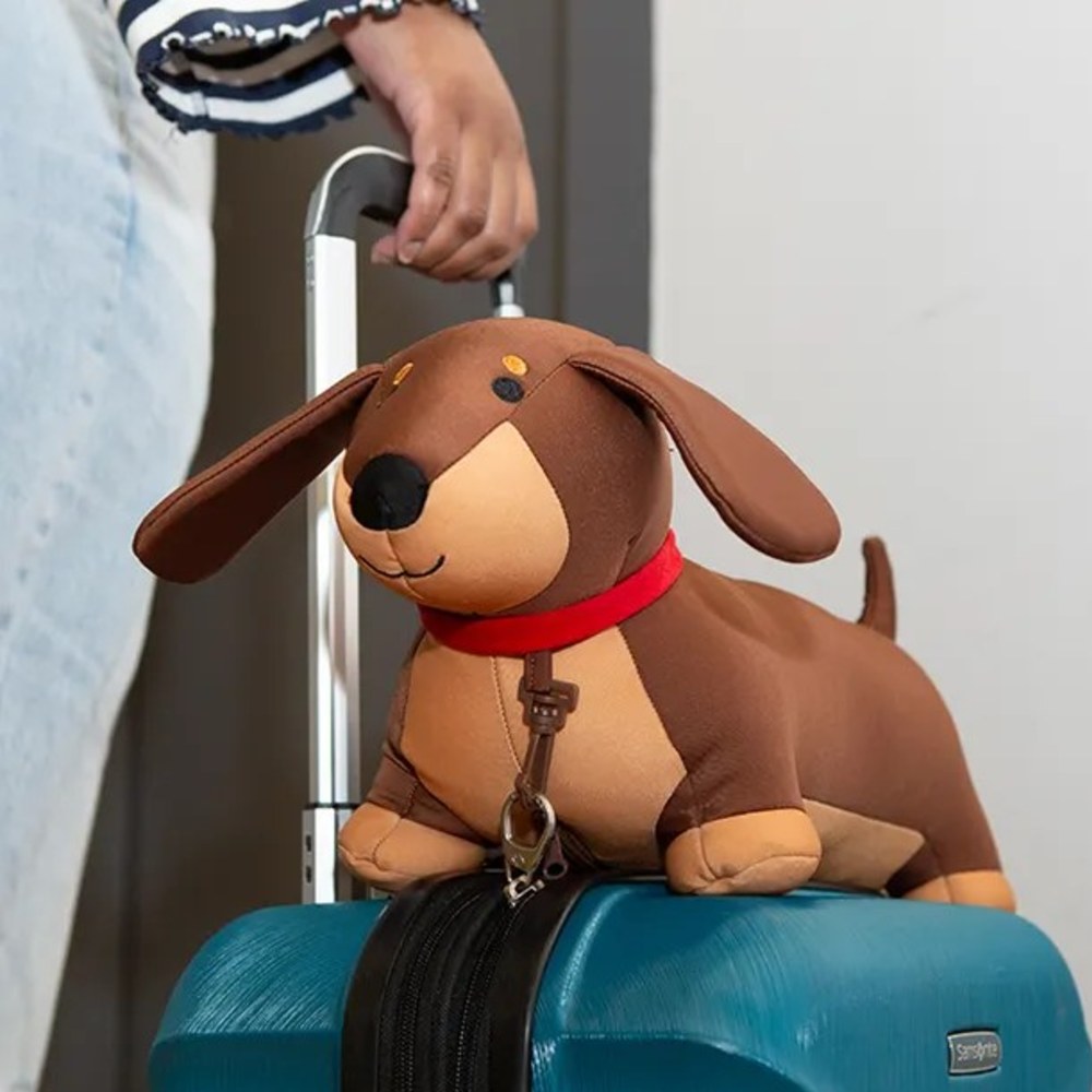 A child's toy dog shown on top of a blue suitcase