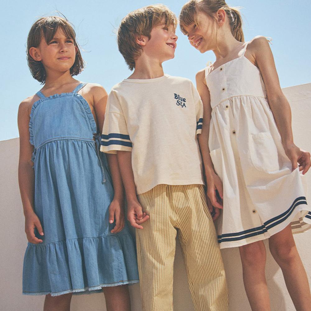 Three children stood outside together wearing summer outfits