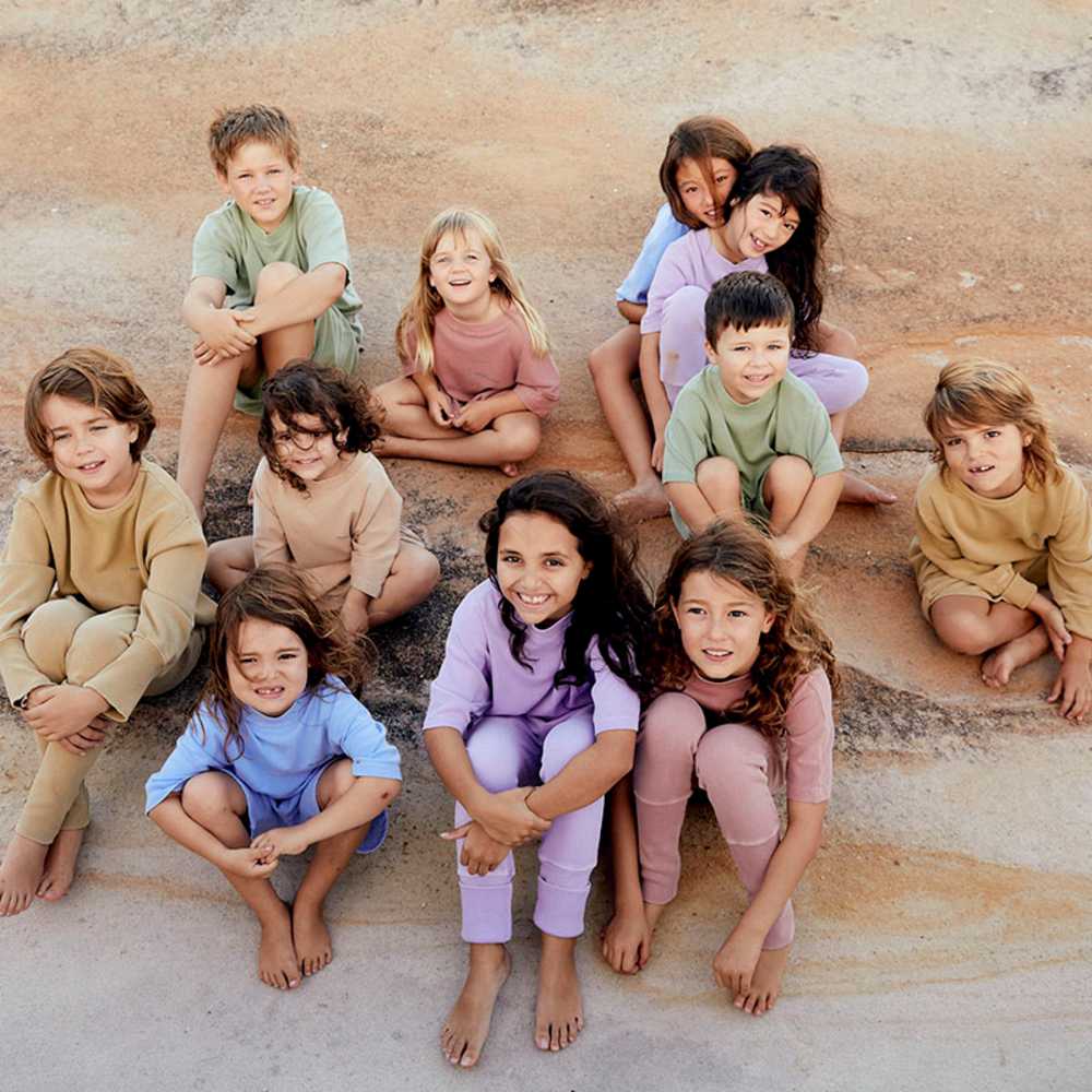 A group of children sat on the floor wearing pastel coloured loungewear 