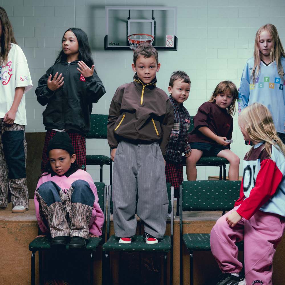 A group of children sat on desks and chairs 