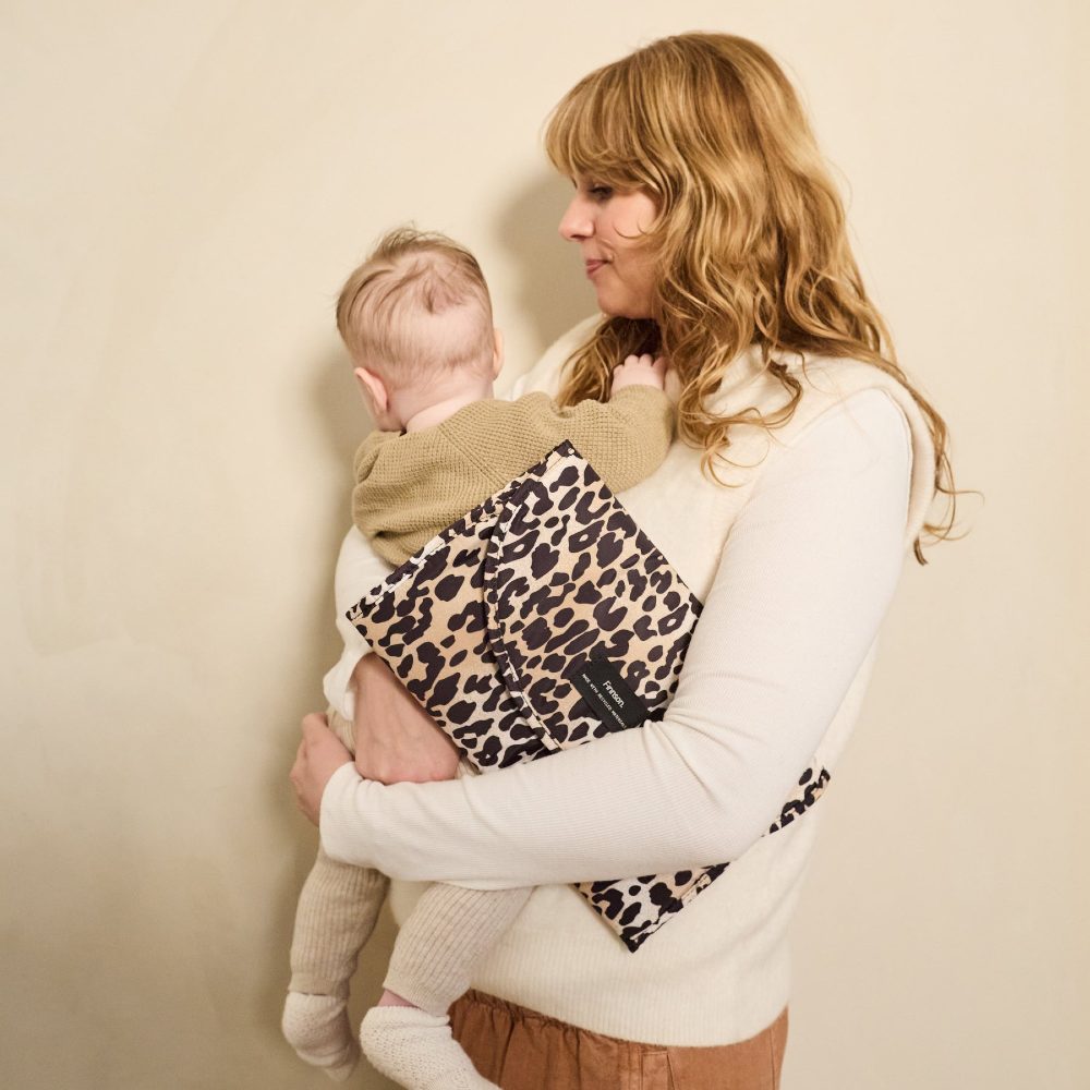 A woman holding a baby and a Finnson clutch changing bag 