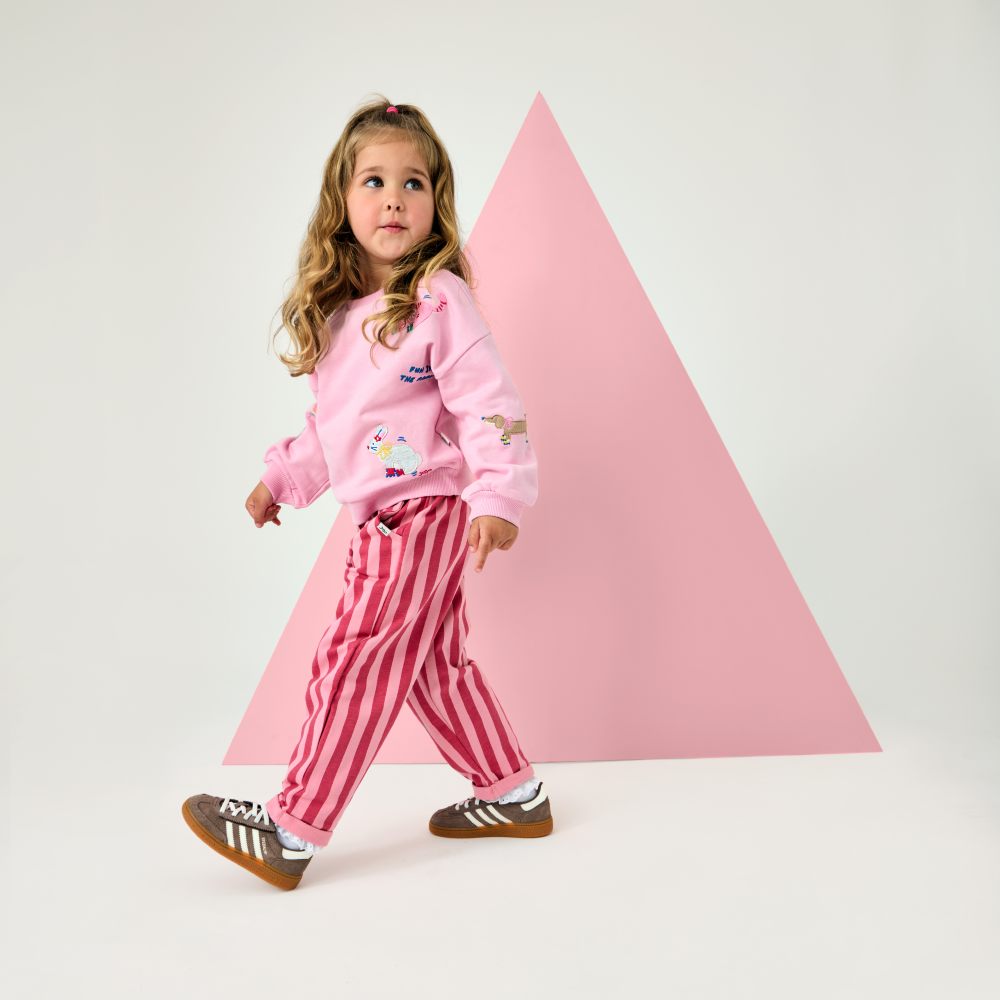 A girl in a pink top and pink striped trousers by JoJo Maman Bebe