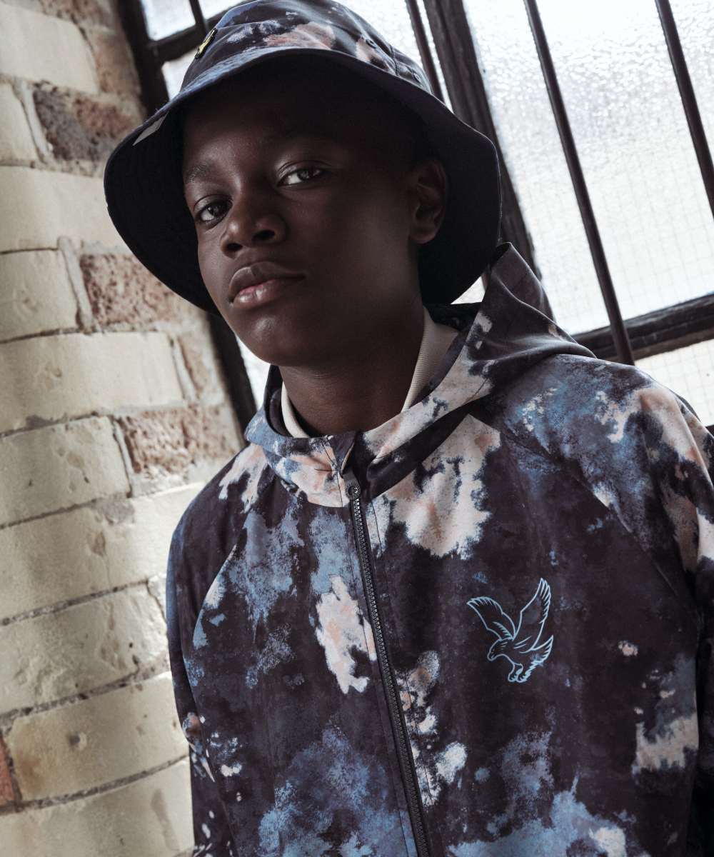 A boy in a matching hat and jacket by Lyle & Scott Kidswear