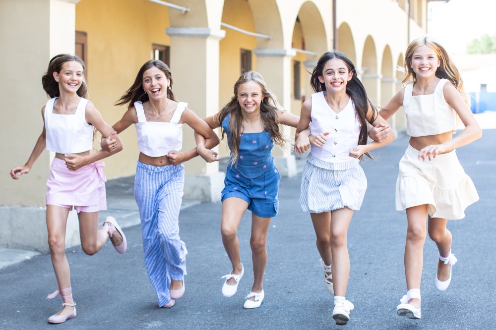 A group of girls in summer outfits running outside at the Pitti Bimbo trade show