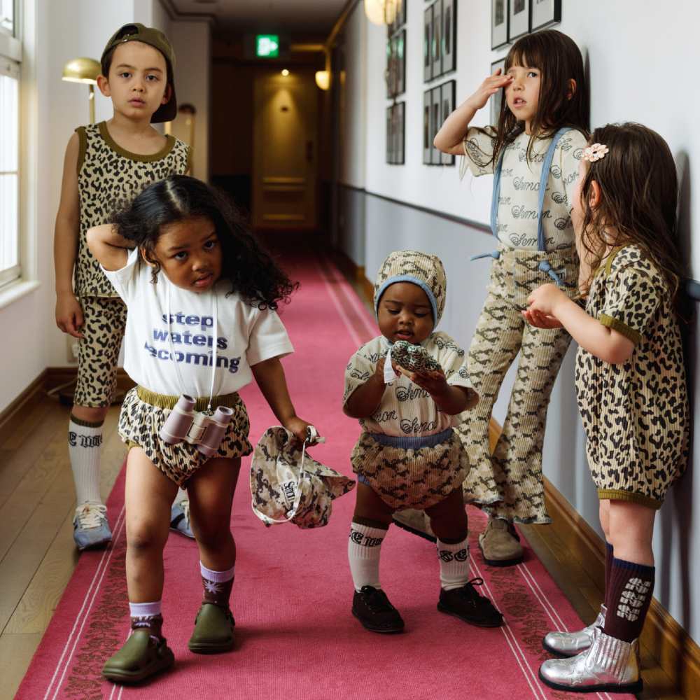A group of children stood in a corridor with a pink carpet 