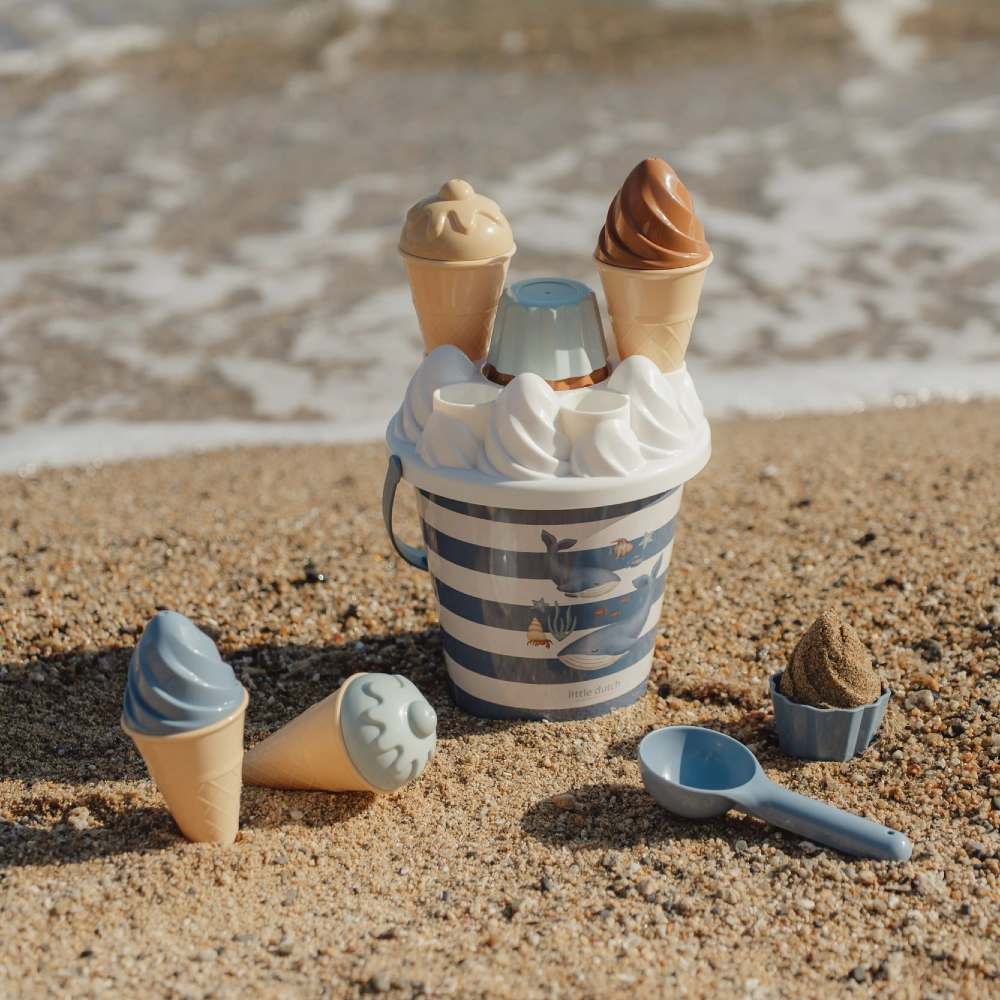 A children's ice-cream bucket and spade toy on a beach
