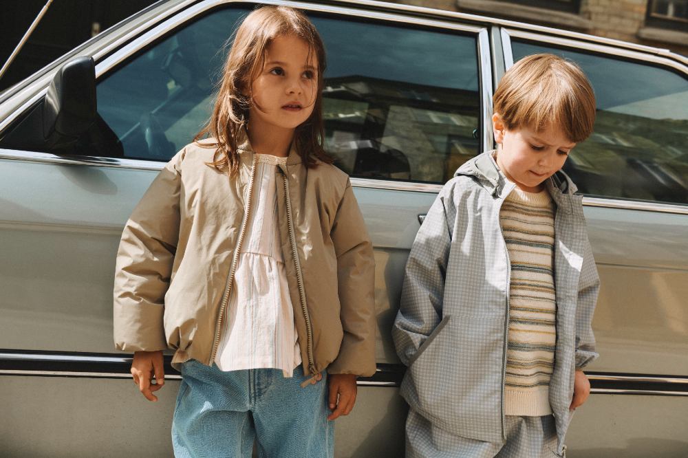 Two children stood beside a car wearing outfits by Wheat