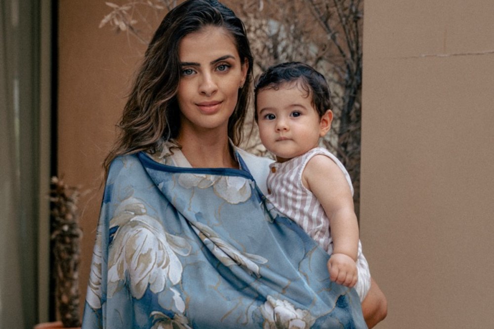 A mother wearing a AuraLai nursing cover holding a young child