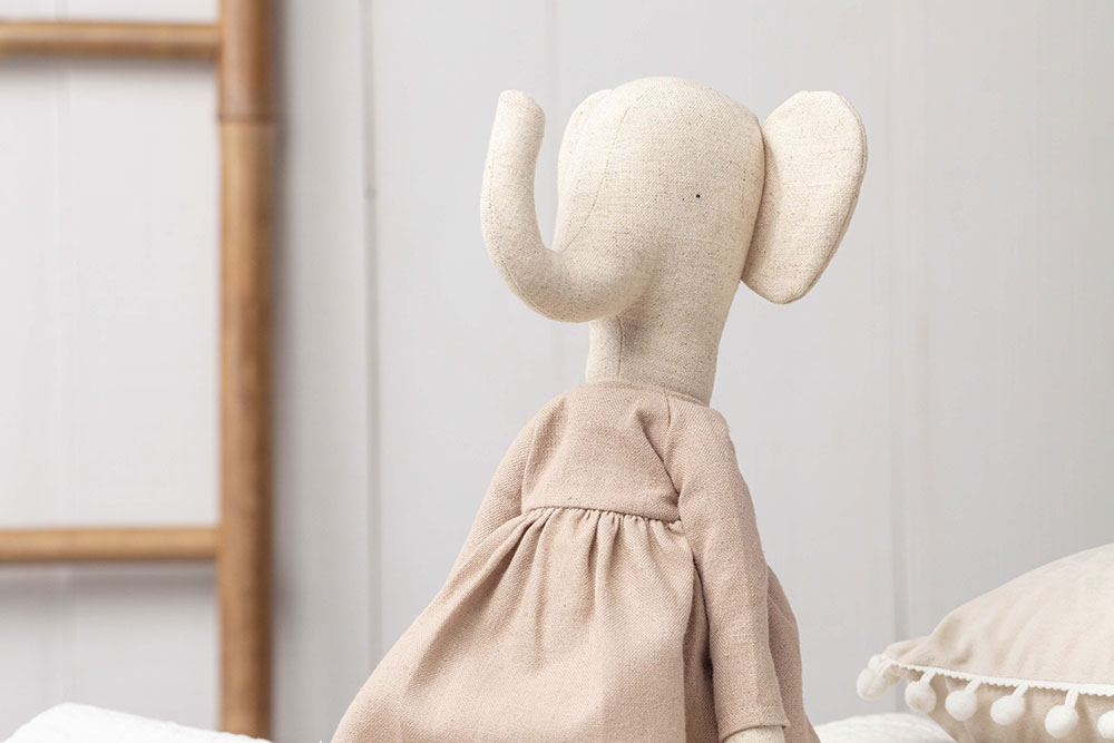 A Pickles plush character sat upright on a bed