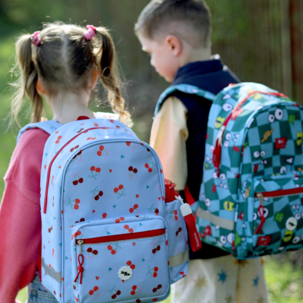 The back of two children outside wearing backpacks by Roamie 