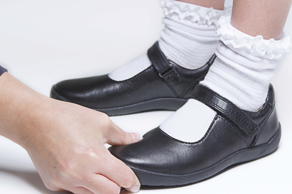 A child's feet in black Start-Rite school shoes being check for size