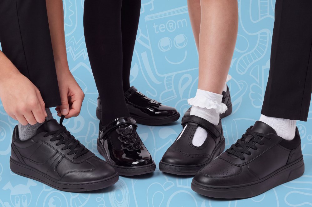 Four school children's legs and feet shown against a blue background wearing black school shoes by Term Footwear