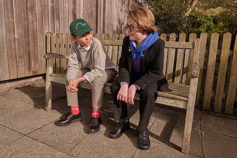 Two boys in schoolwear sat outside on a wooden bench